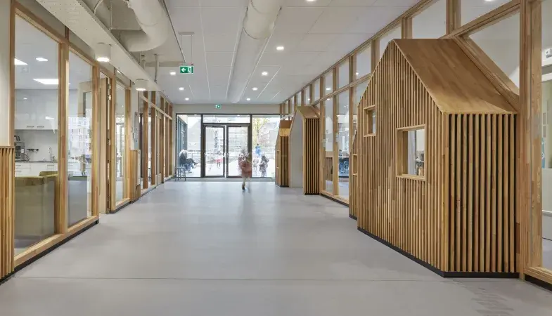 Világos iskolai folyosó fa design elemekkel és tartós közületi padlóval.